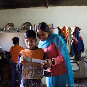 Veena, a young mother in Janta Colony, helping her sons with schoolwork.