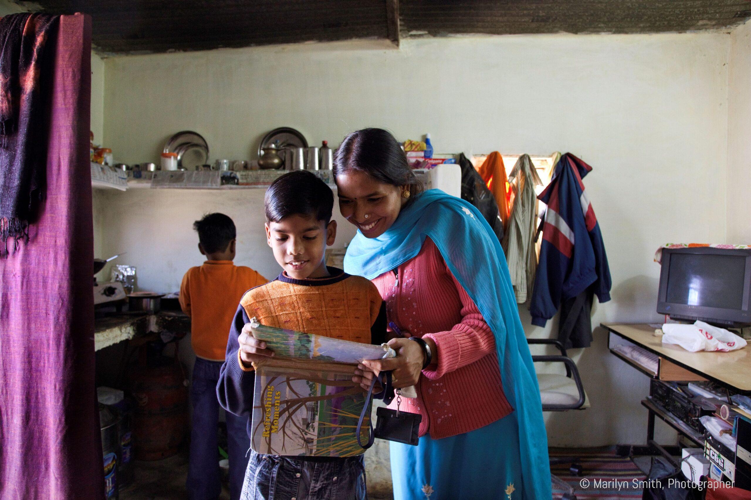 Veena, a young mother in Janta Colony, helping her sons with schoolwork.
