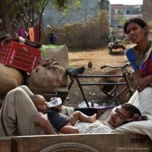 A young mother looks on while her husband feeds the baby.