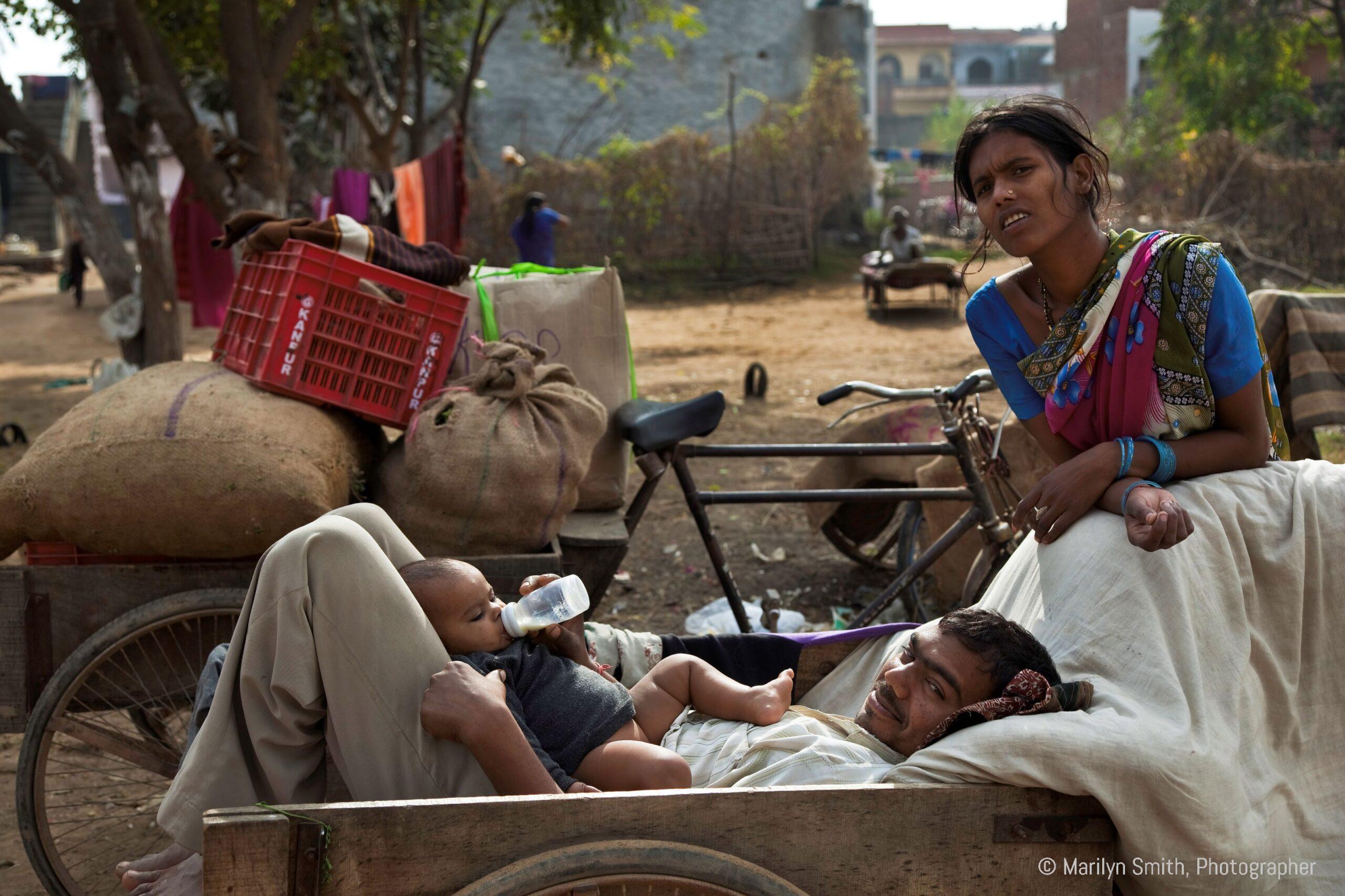 A young mother looks on while her husband feeds the baby.