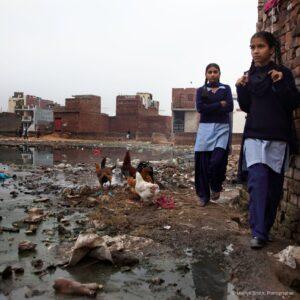 School girls navigating the edge of the swamp in Janta Colony.