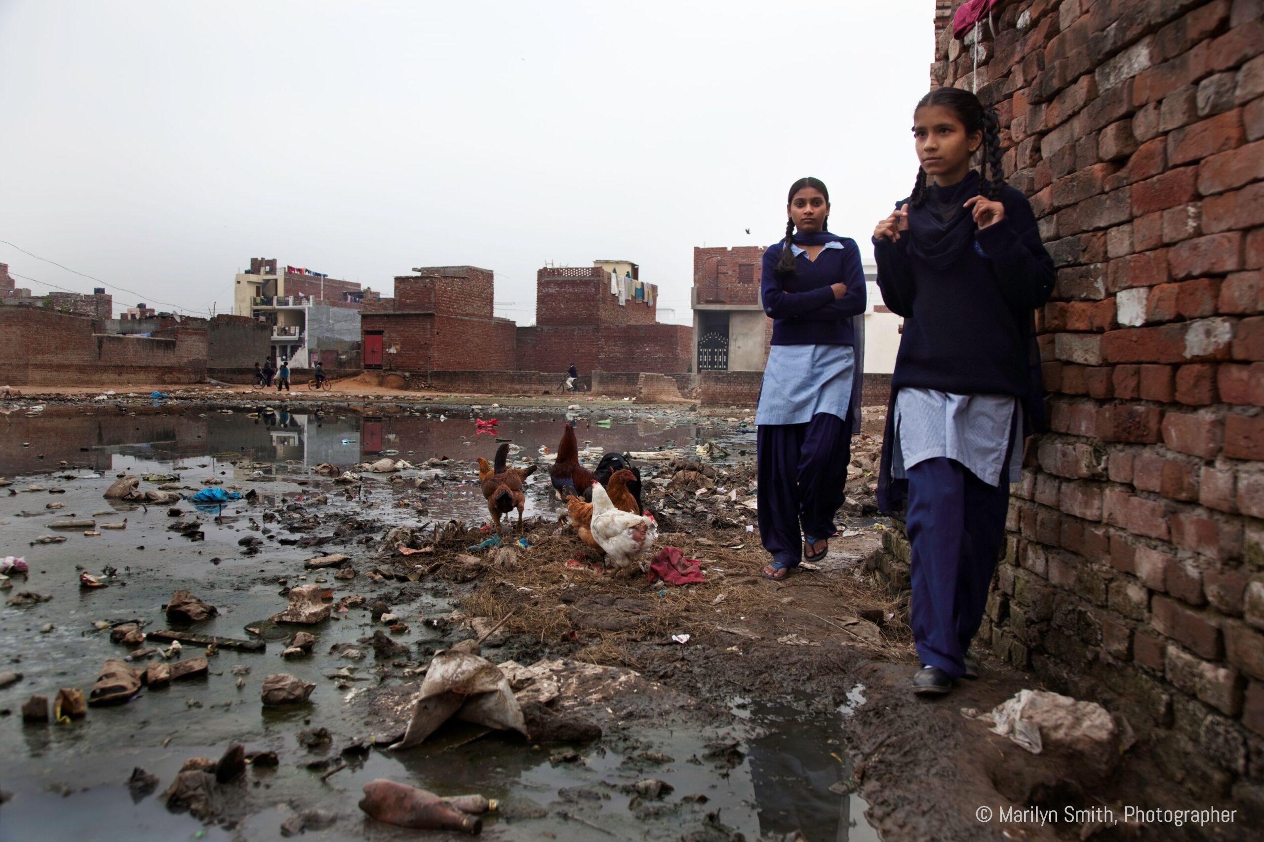 School girls navigating the edge of the swamp in Janta Colony.