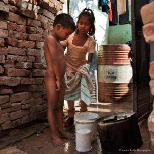 A young girl bathing her younger brother.