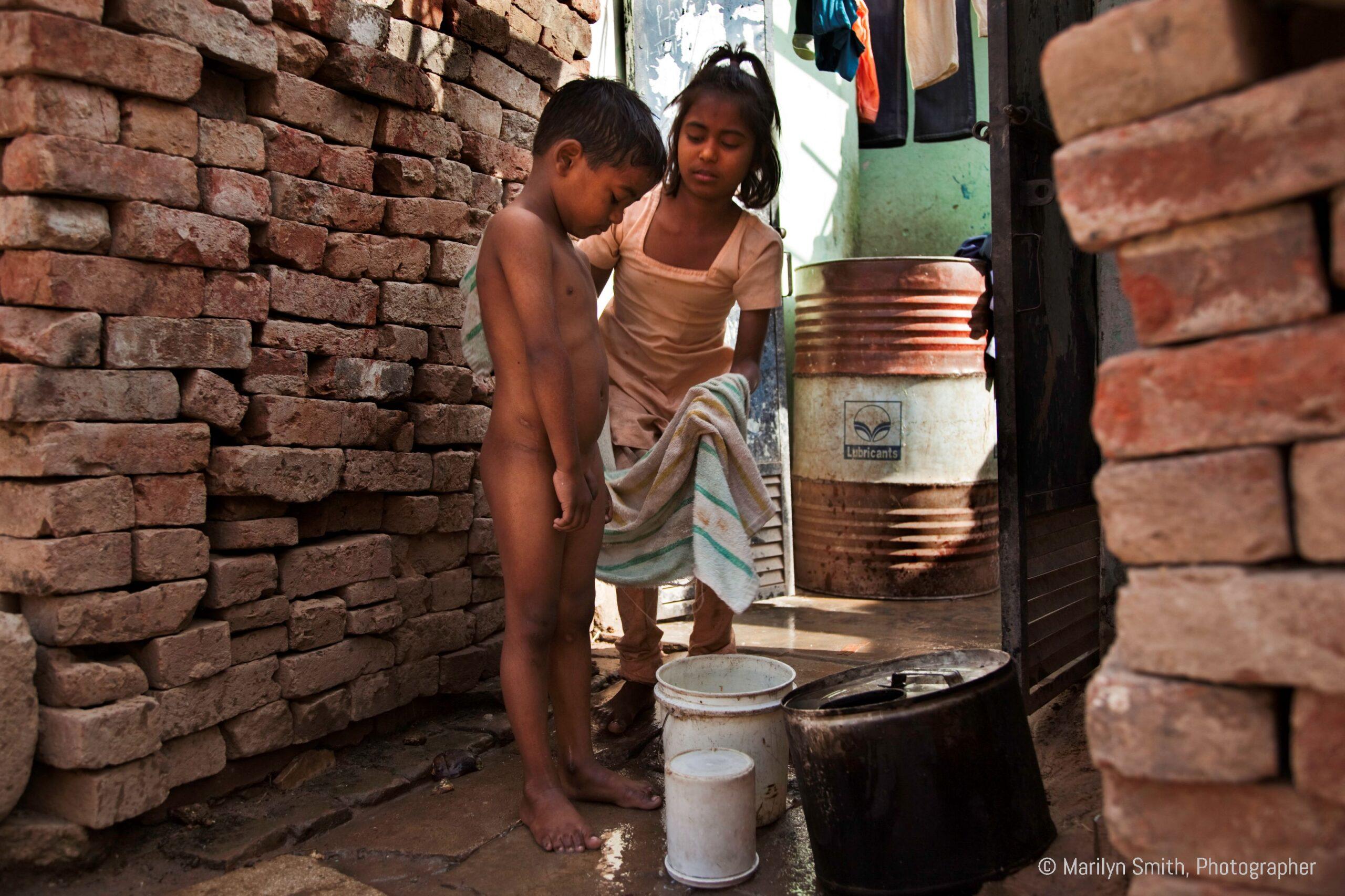 A young girl bathing her younger brother.