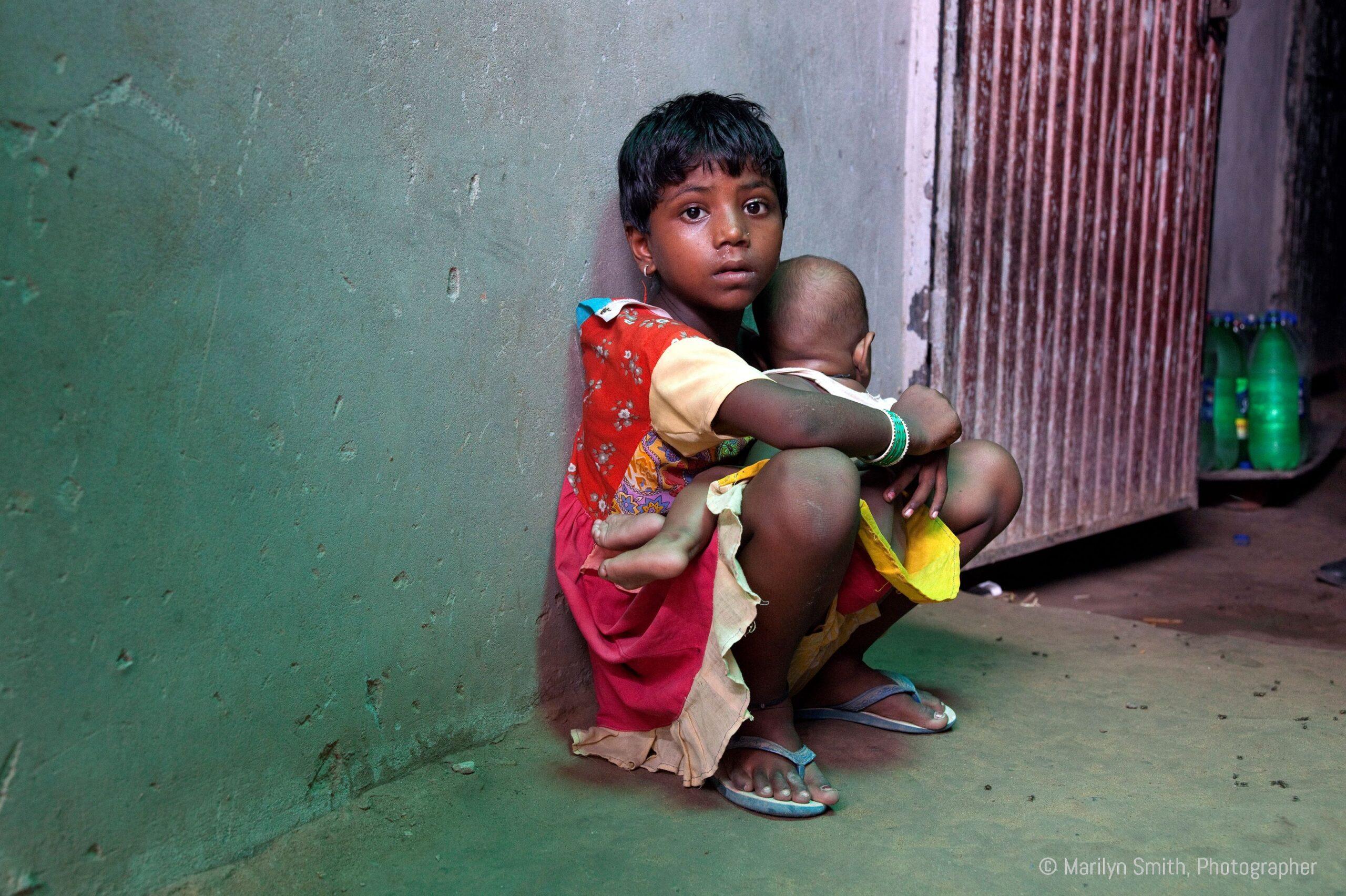 A young girl taking care of younger siblings.
