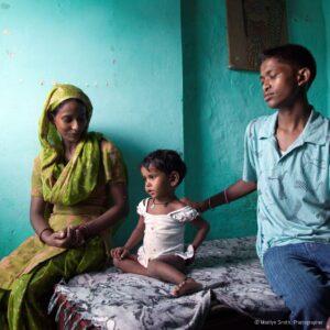 A teenage boy helps educate a woman about child care and nutrition in Janta Colony.