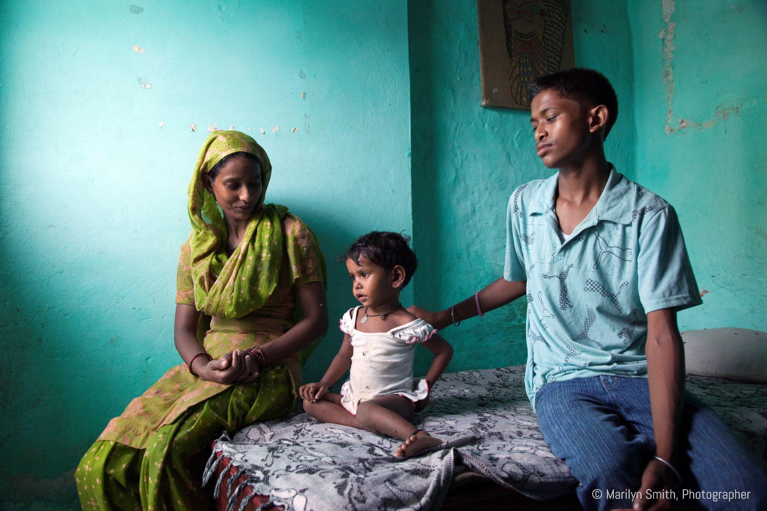 A teenage boy helps educate a woman about child care and nutrition in Janta Colony.