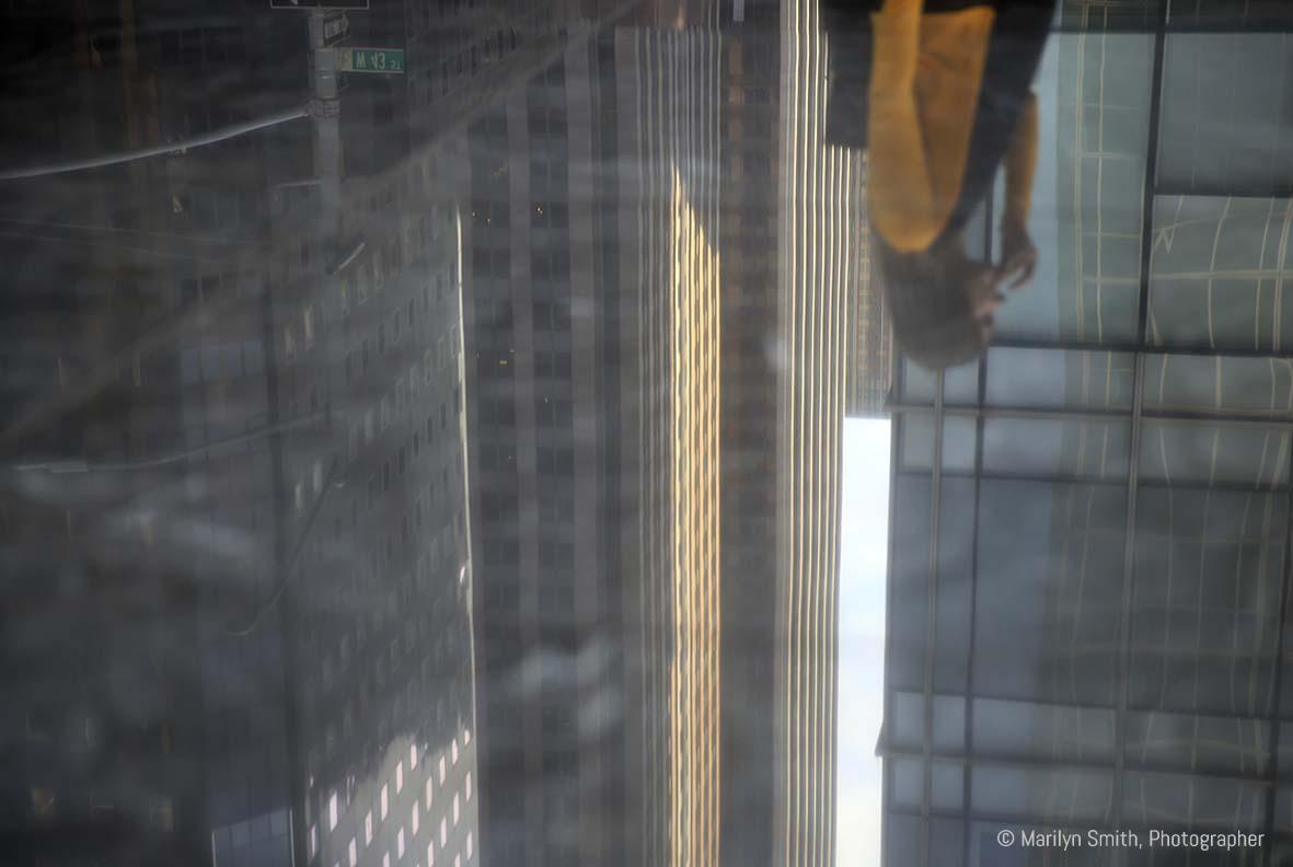 A woman walking after work, reflected in polished granite, New York City.